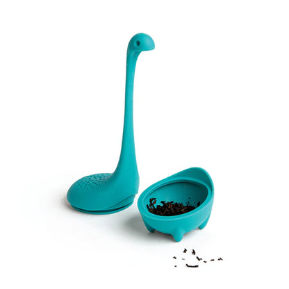 Teal dinosaur-shaped tea infuser with a small bowl on a white background